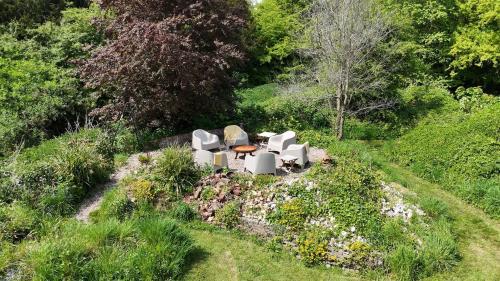 two white chairs and a table in a garden at Unique & Rural Child Friendly Annexe with Large Gardens, Games & Tennis Court - Chichester Holiday Properties in Chichester