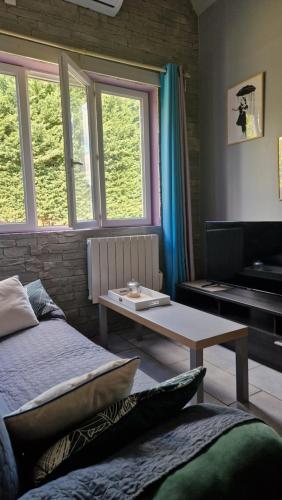 a room with a bed and a table and windows at La tranquille maison bleue 