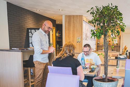 a man standing in an office talking to two people at Kyriad Nancy Sud - Ludres in Ludres