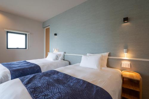 a hotel room with two beds and a window at TIMeSCAPE -tancha- in Onna