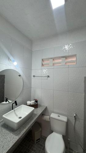 a white bathroom with a toilet and a sink at Hotel Americas in Fortaleza