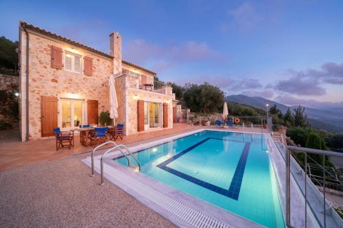 a villa with a swimming pool in front of a house at Kamini by Vintage Travel in Dhefaranáta