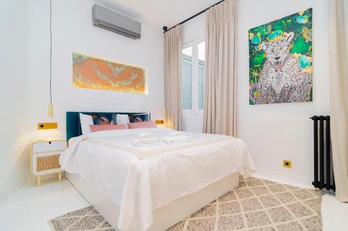 a white bedroom with a large bed and a painting at Luxury Golden Apartamento a solo pasos de Gran Vía in Madrid