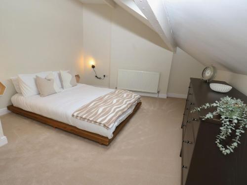 Un dormitorio blanco con una cama y una cómoda con una mesa. en 11 Bronte Street, en Haworth
