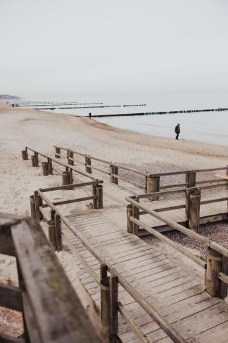 a person walking on the beach next to a pier at Parkhotel IV Jahreszeiten Kühlungsborn in Kühlungsborn