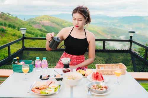 Una donna seduta a un tavolo con sopra del cibo di สกายวิวคาเฟ่&โฮมสเตย์ a Ban San Pu Loei