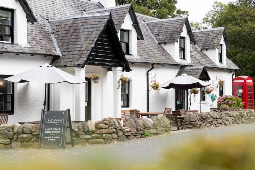 a white building with an umbrella and tables and chairs at Ardeonaig Hotel & Restaurant in Ardeonaig