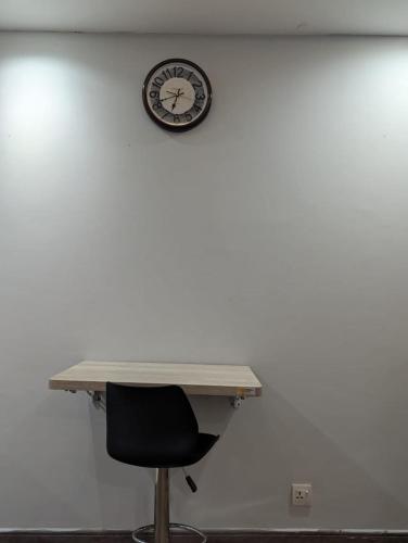 a desk with a chair and a clock on a wall at Luxury Apartments at Goldcrest Mall and Residency DHA Phase 4 by Nirvana Nests in Lahore