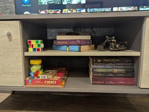 a book shelf with books and other toys on it at Luxury Apartments at Goldcrest Mall and Residency DHA Phase 4 by Nirvana Nests in Lahore