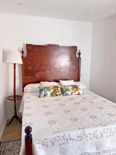 a bed with a wooden headboard and a white blanket at Casa Milamores Constância in Constância