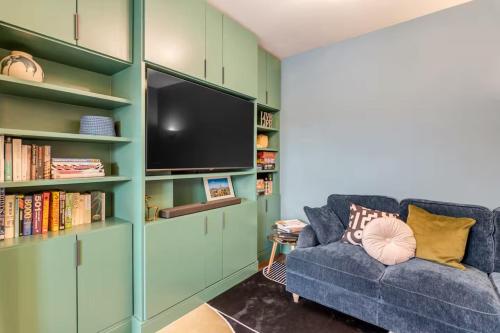a living room with a blue couch and a tv at Eco Friendly Luxury Townhouse with Parking in Norwich