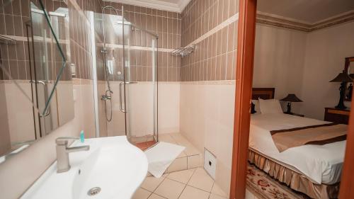a bathroom with a shower and a sink and a bed at Résidence Hôtelière Le Jomonia in Libreville