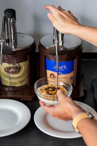 a person pouring peanut butter into a bowl of food at International Hotel & Suite in San Benedetto del Tronto
