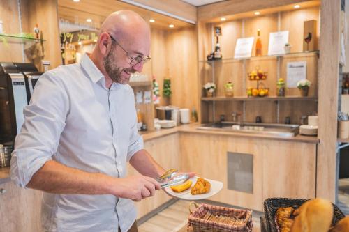 a man holding a plate of food in a kitchen at Kyriad Nancy Sud - Ludres in Ludres