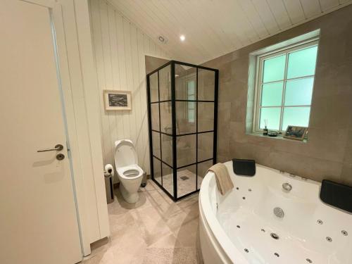 a bathroom with a tub and a toilet at Lovely Black Wooden House Near Tisvilde Hegn in Tisvilde