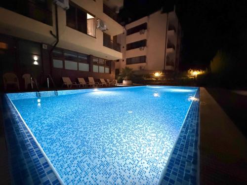 ブルガスにあるHome by the Seaの夜間の建物内の大型スイミングプール
