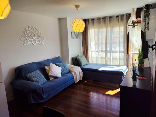 a living room with a blue couch and a window at Flor de Lis in Medina de Pomar