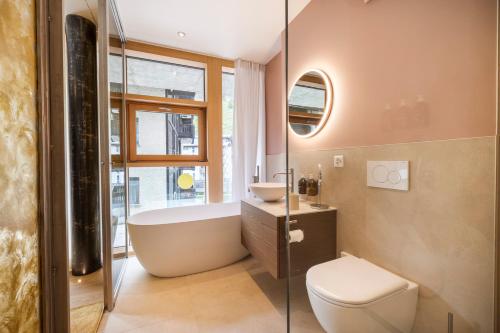 a bathroom with a tub and a toilet and a sink at Face d'Or in Zermatt
