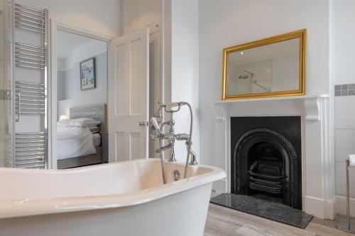a white bath tub in a bathroom with a fireplace at Sole Rose in Southwold
