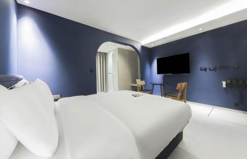 a bedroom with a white bed and a blue wall at 뮤트호텔 대연 MUTE HOTEL Daeyeon Busan in Busan