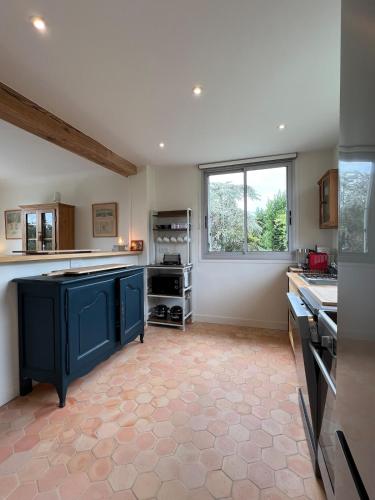 une grande cuisine avec des placards bleus et une fenêtre dans l'établissement Maison Passiflora, à Trouville-sur-Mer