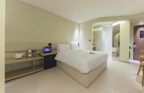 a bedroom with a large bed and a desk with a television at 뮤트호텔 대연 MUTE HOTEL Daeyeon Busan in Busan