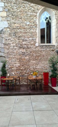 a patio with tables and chairs in front of a brick building at La Suite Quatre de Saint Jean in Crémieu