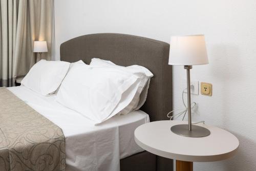 a bed with white pillows and a table with a lamp at Piazzi House in Sondrio