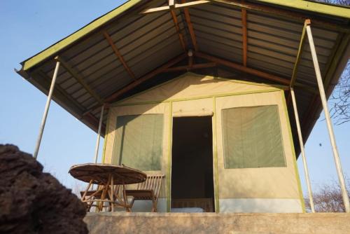 una casa con tetto con tavolo e panca di Oldonyo Musa Camp Amboseli a Rift Valley