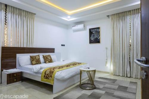 Un dormitorio con una cama grande y una mesa. en Luxurious Abuja Apartment with Modern Amenities, en Jabi