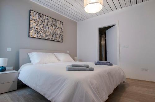 a bedroom with a large white bed with towels on it at Chic 2BR Apartment Steps from the Gzira Seafront in Il-Gżira