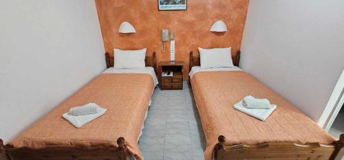 2 Betten in einem kleinen Zimmer mit Handtüchern darauf in der Unterkunft Hotel Palladion in Karterados