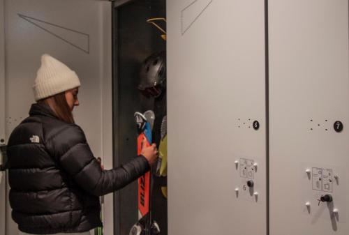 a person in a black jacket holding a snowboard at Camping Essenza Alpina in Folgaria