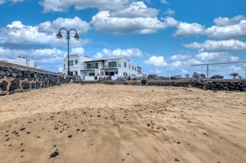 a beach with footprints in the sand and buildings at Apartamento El Charcon B - 10 meters to the Beach By Lanzarote Vacation Homes in Arrieta