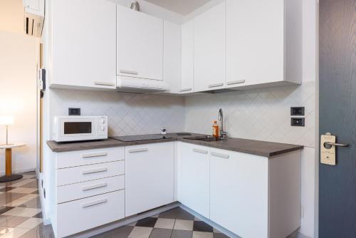 a kitchen with white cabinets and a microwave at Piazzi House in Sondrio
