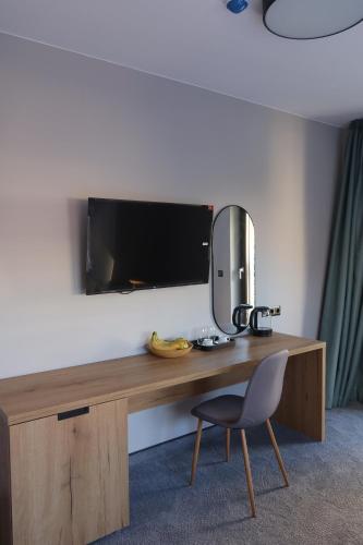 Un escritorio con un televisor y una silla en una habitación. en Acacia Hotel, en Sofía