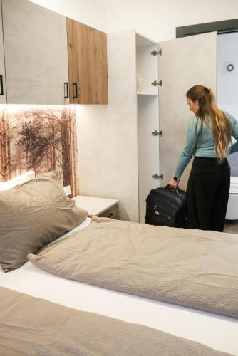 a woman with a suitcase standing next to a bed at Camping Essenza Alpina in Folgaria