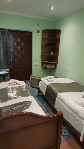 two beds in a room with green walls at Dilbo House in Dilijan