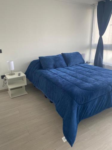un letto blu con una coperta blu in una camera da letto di Hermoso Departamento nuevo en Laguna del Mar La Serena a La Serena