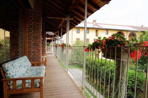 a porch with a bench and flowers on a fence at Cascina delle Mele in Vittuone