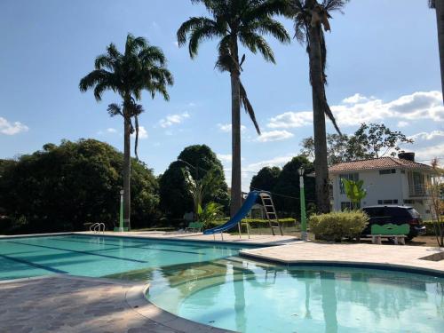 a swimming pool with a slide and palm trees at Hermosa cabaña cerca Restrepo in Villavicencio