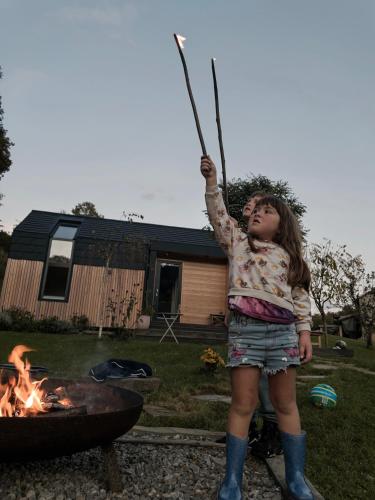 a little girl holding a stick in front of a fire at Posestvo Brida - Brkini Hills by the Lakes in Ilirska Bistrica