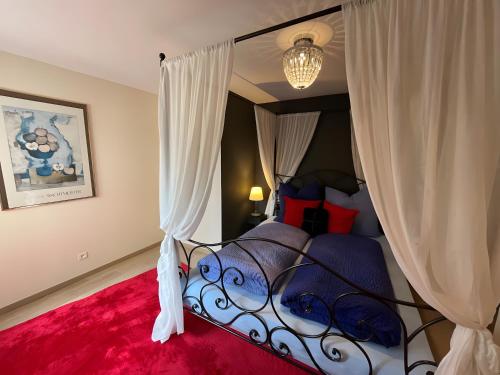 - une chambre avec un lit à baldaquin et un tapis rouge dans l'établissement Gite Bleu - Paradis de Provence, à Le Pin