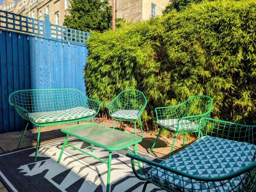 four green chairs and a table in front of a fence at Old Farmhouse - Brand New Apartment - Free Parking - Central Bath in Bath