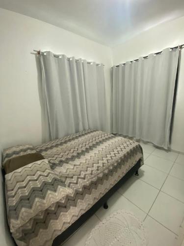 a bed in a room with curtains in a room at Casa em condomínio próximo a COP 30 in Belém