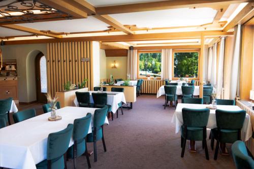 a dining room with white tables and green chairs at Hotel Kniebis-Stuben in Kniebis
