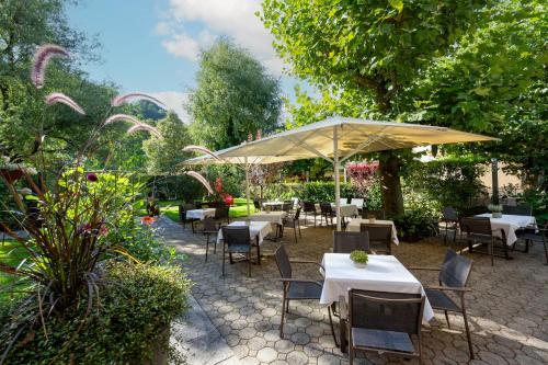 a patio with tables and chairs and an umbrella at Relax & Vitalhotel Adler in Schruns-Tschagguns