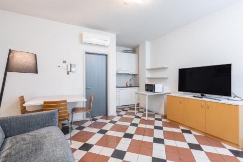 a living room with a couch and a tv and a kitchen at Piazzi House in Sondrio