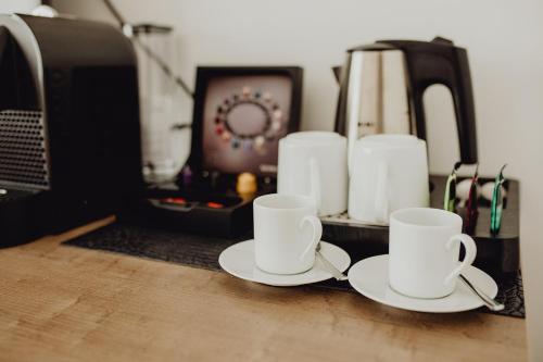 two white coffee cups sitting on a counter with a microwave at Art & Business Hotel in Nuremberg