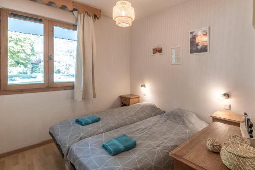 two twin beds in a room with a window at Appartement à Samoëns – 6 couchages in Samoëns